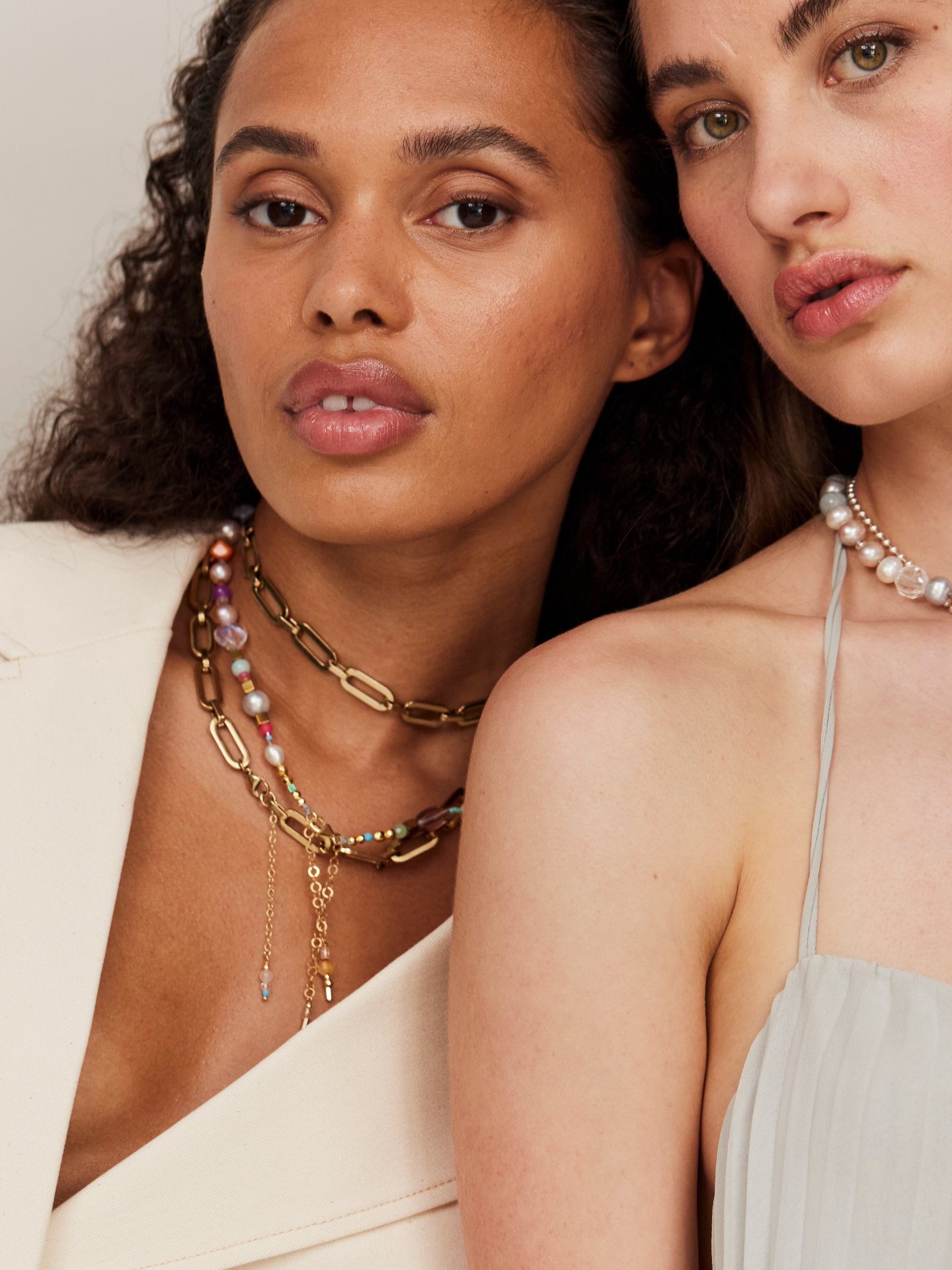 Zwei wunderschöne Frauen schauen in die Kamera und tragen tollen, exzentrischen Schmuck mit Perlen und hohem Designanspruch.