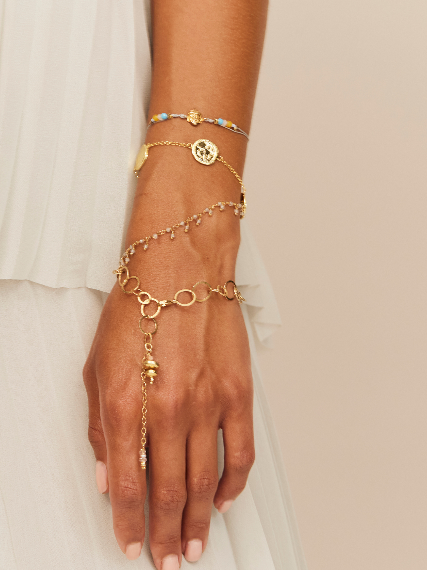 Großaufnahme einer Hand mit goldenem verspieltem Armband mit langem Anhänger.