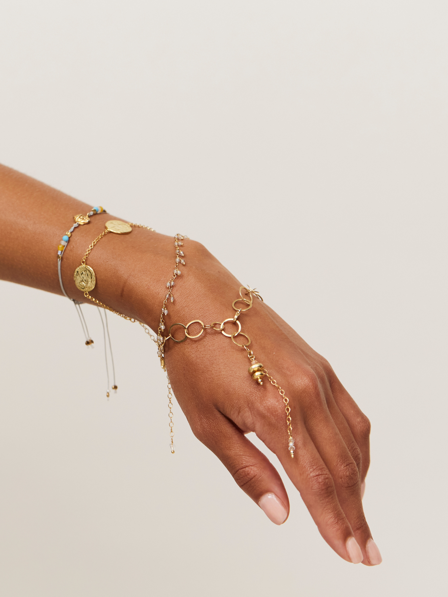 Großaufnahme einer Hand mit goldenem verspieltem Armband mit langem Anhänger.