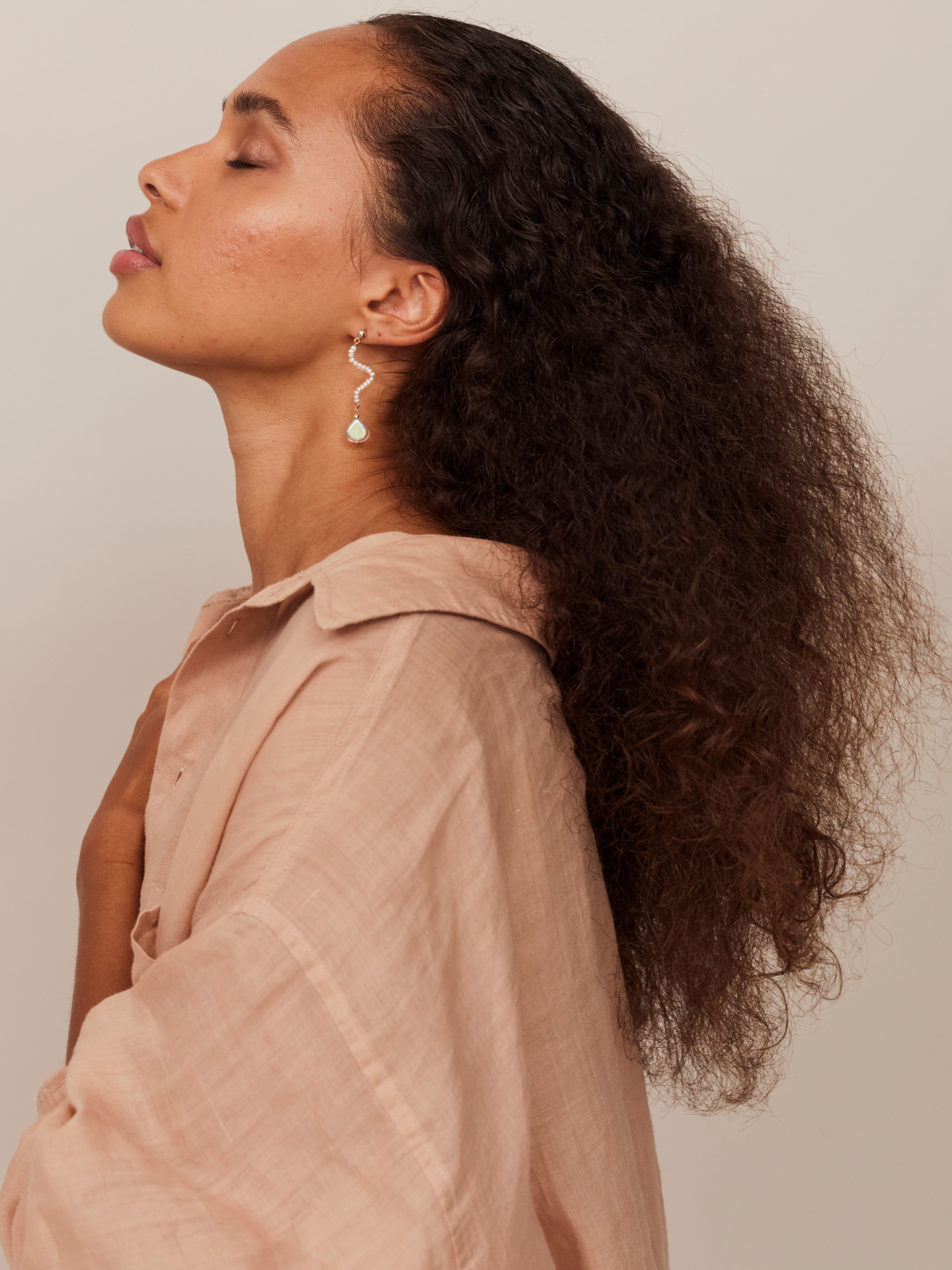 Attraktive Frau mit geschlossenen Augen trägt einen Ohrring aus Sterling Silber, bestehend aus vielen kleinen Perlen, verfeinert mit Bergkristallen.