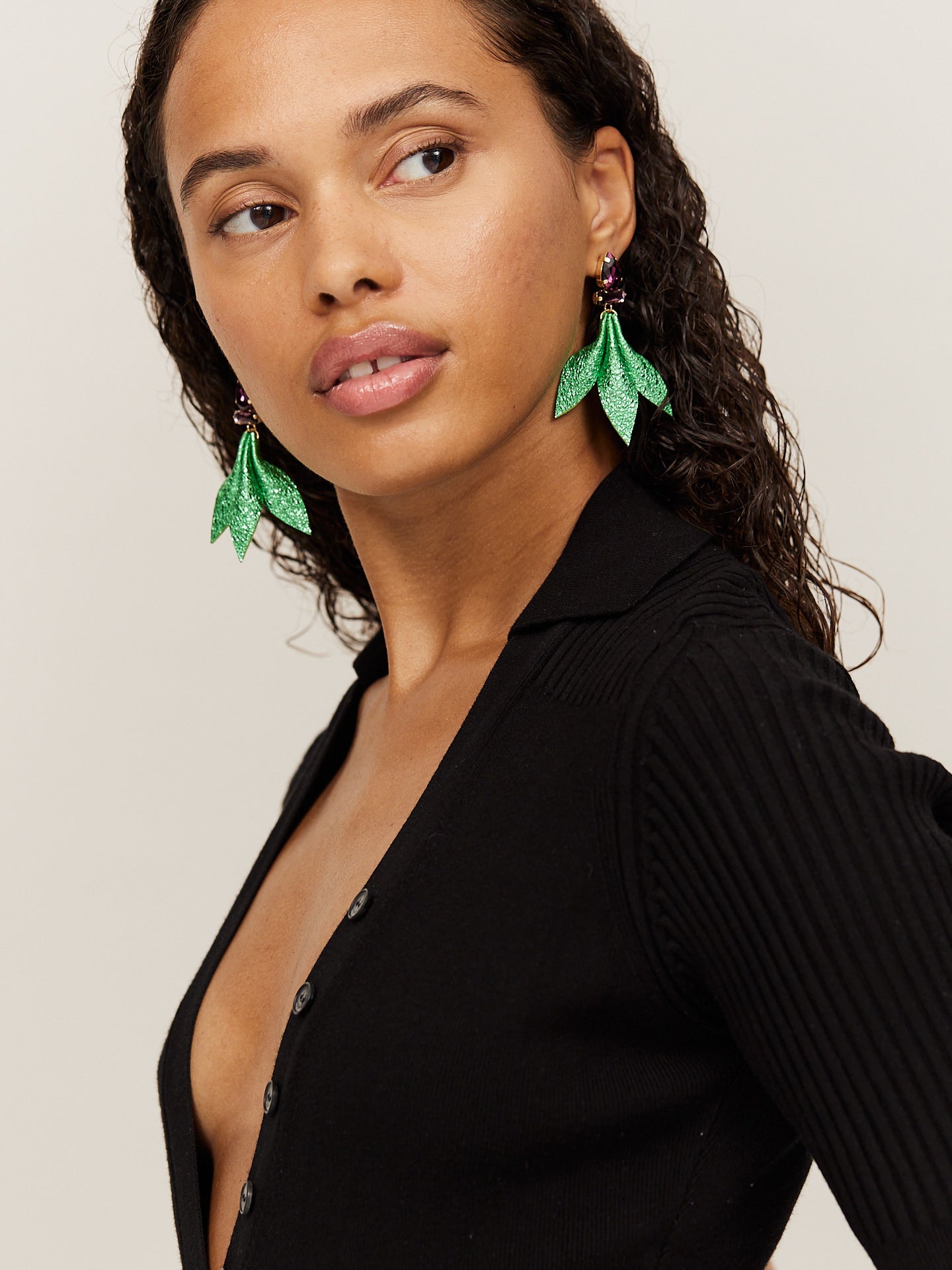 Attraktive Frau mit schwarzem Body trägt wunderschöne, grüne Nappa Leder Ohrringe und schaut an der Kamera vorbei.