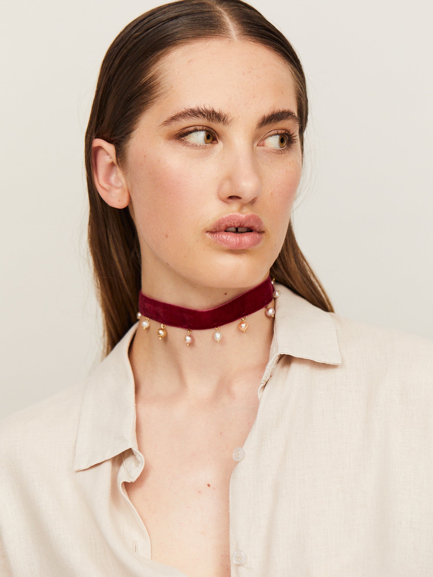 Eine Frau mit sinnlichen Lippen trägt einen handgefertigten Choker, an dem Perlen in Abständen hängen.