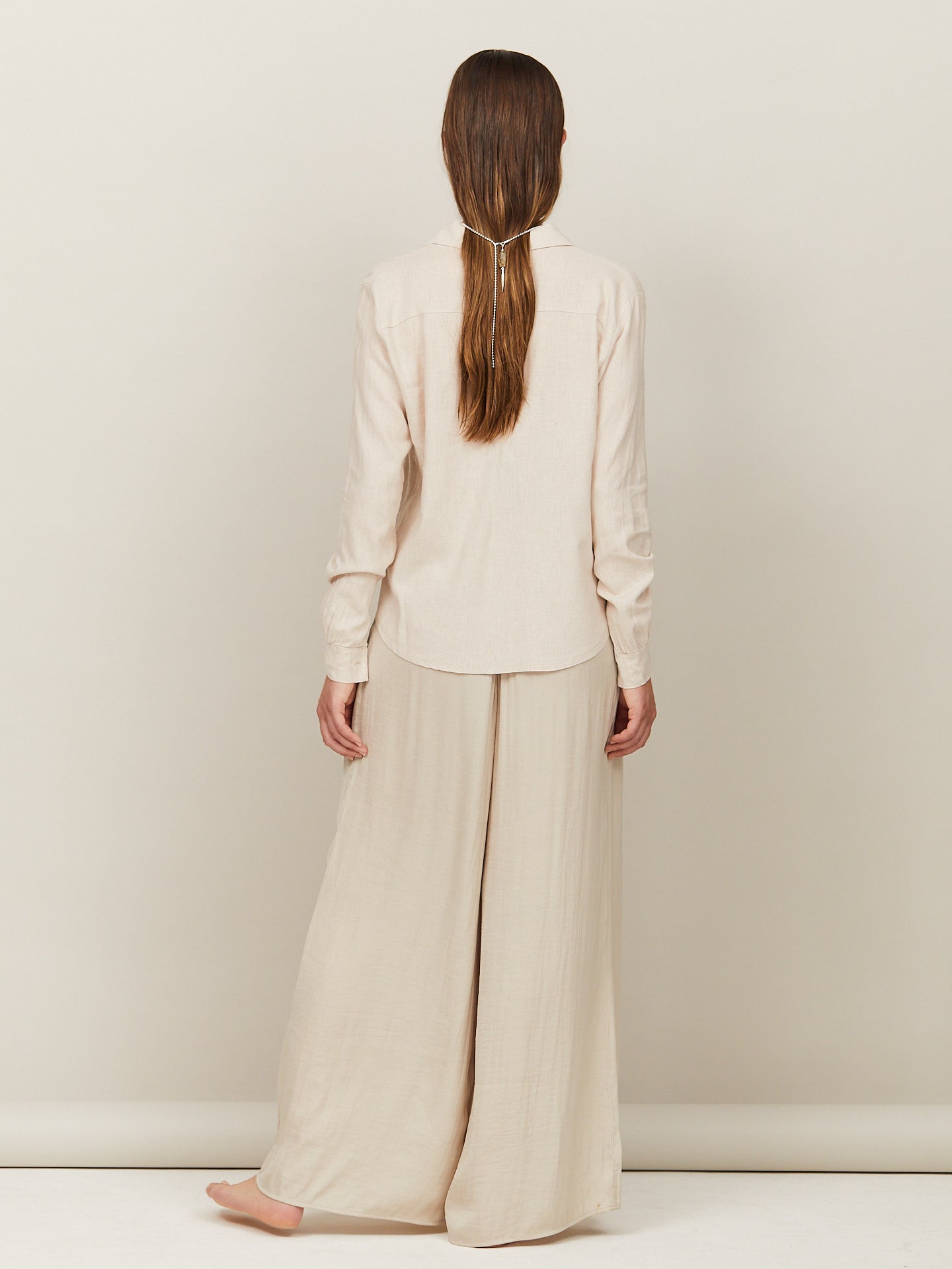 Braunhaarige Frau trägt eine zarte silberne Kette mit einem aufregenden Anhänger im Haar.