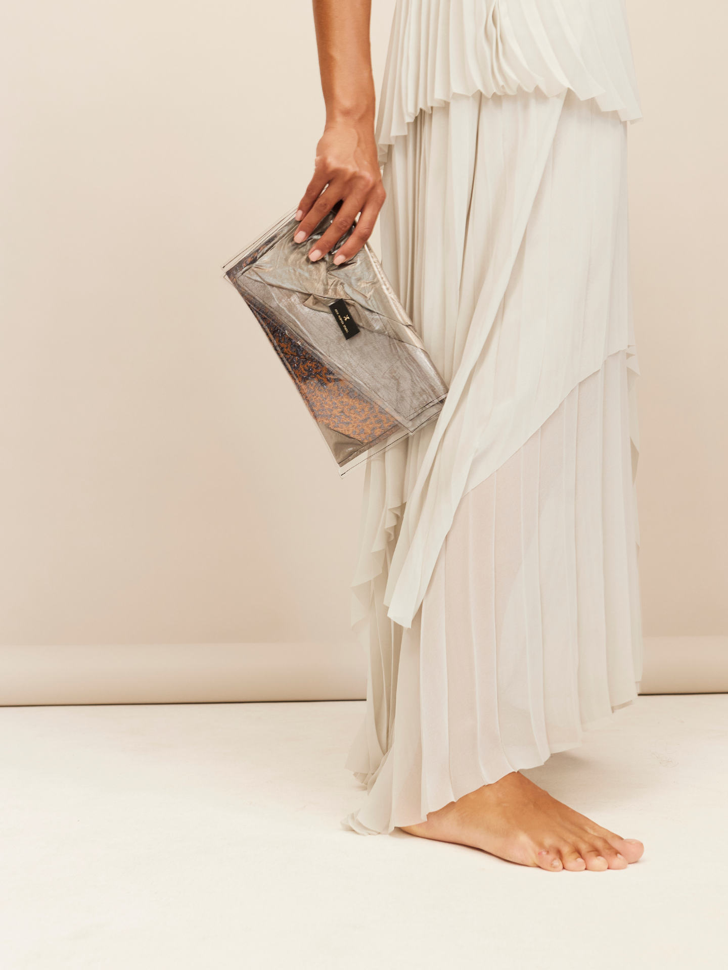 Frau in hellem Kleid trägt eine Tasche aus verschiedenen Designerstoffen, als Kunstwerk dargestellt und als Tasche gebündelt.