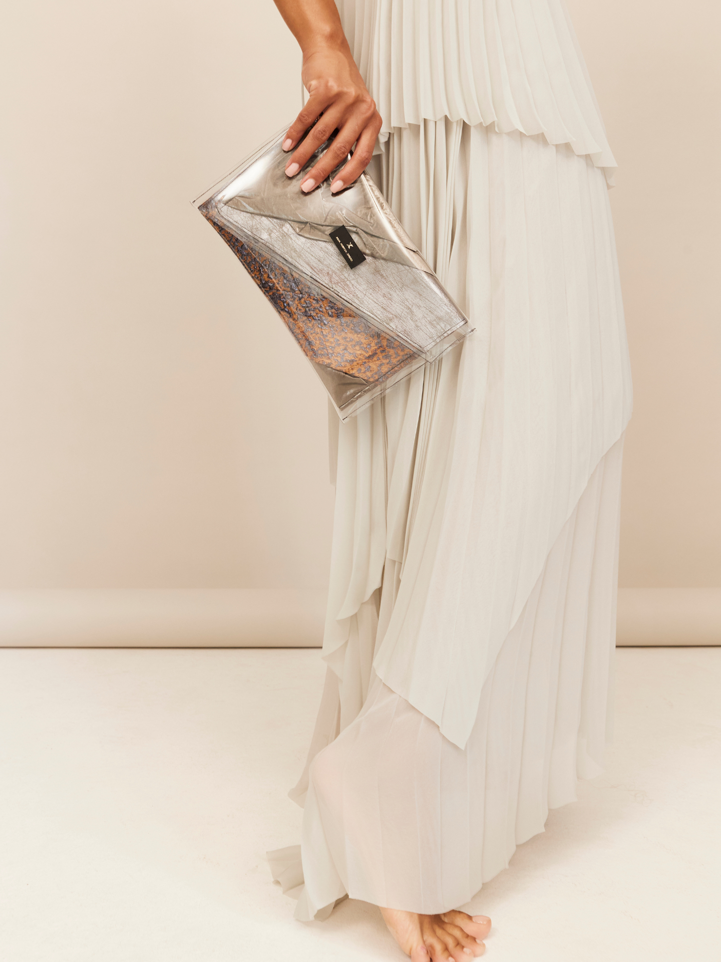 Frau in hellem Kleid trägt eine Tasche aus verschiedenen Designerstoffen, als Kunstwerk dargestellt und als Tasche gebündelt.