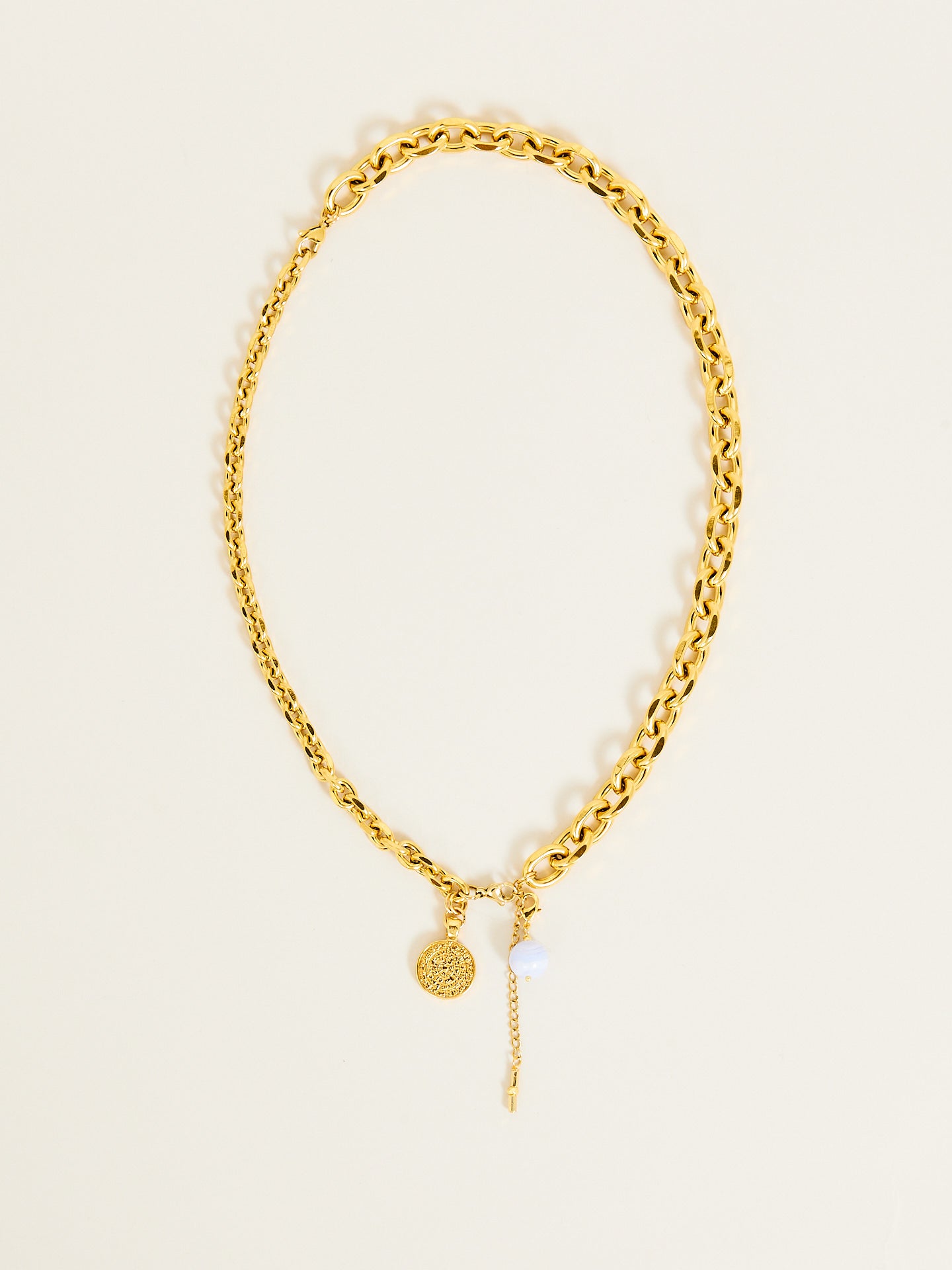 Goldene Halskette mit Münze und Perle als Anhänger.