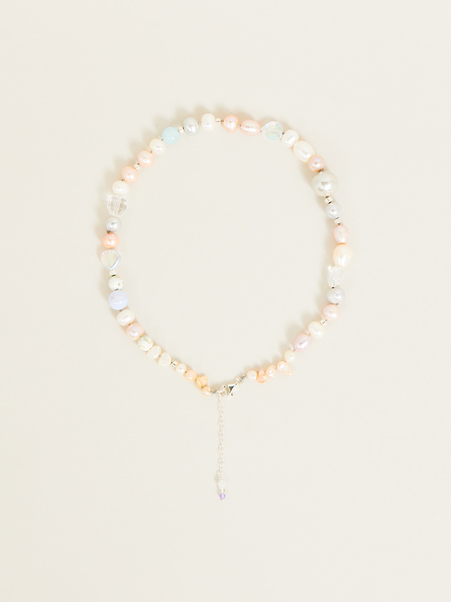 eine Perlenkette in Pastellfarben mit einem kleinen Anhänger.