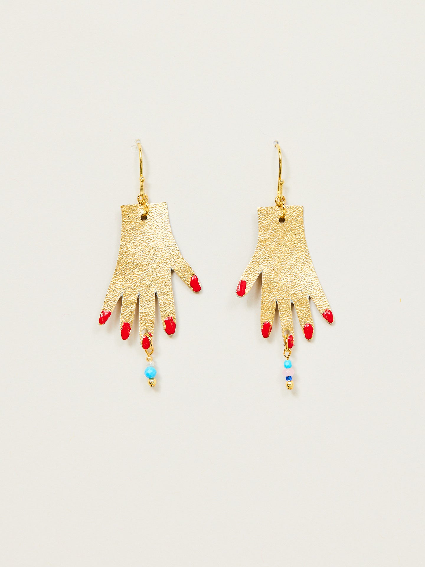 Ohrringe, die zwei goldene Hände mit rotem Nagellack symbolisieren.