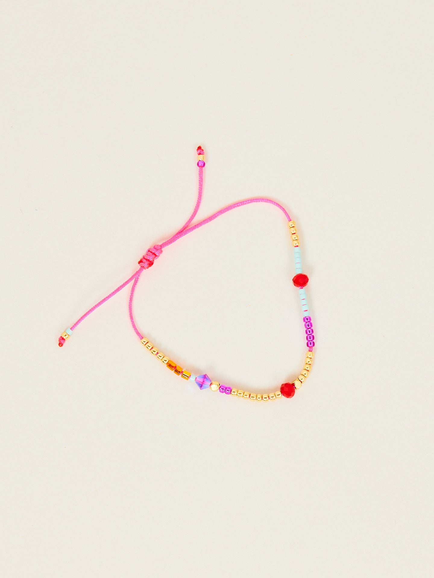 Kreatives Armband in bunten Farben mit einem pinken Bändchen.